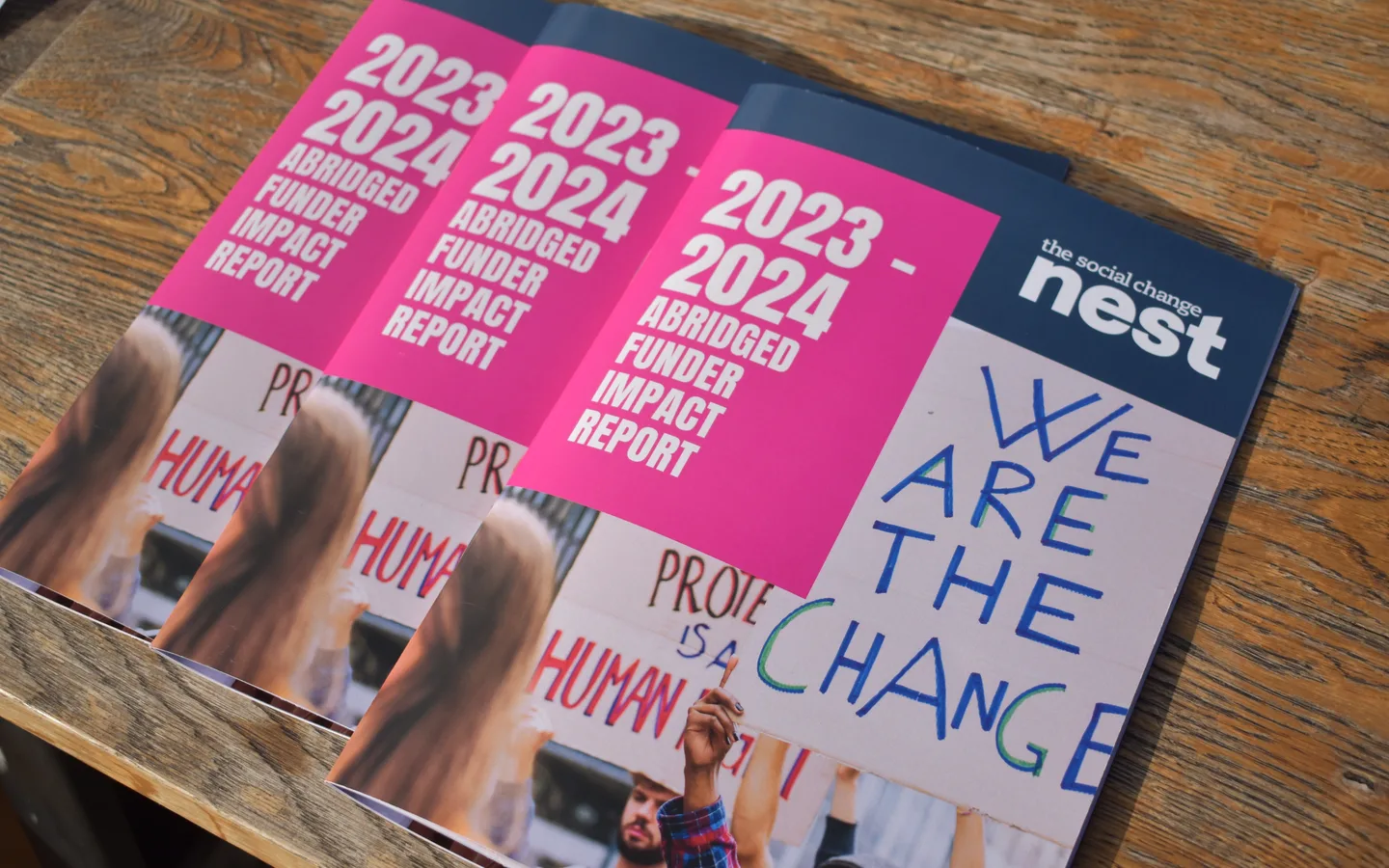 Printed copies of The Social Change Nest’s 2023 to 2024 funder impact report on a table